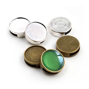 Peut inclure: Assortiment de sertis ronds en métal pour la fabrication de bijoux. Les sertis sont de couleur argent et bronze et ont une finition lisse et brillante. Certains sertis ont un design texturé. Un serti a un cabochon en verre vert.