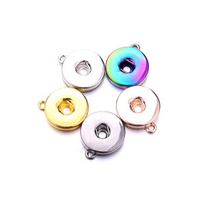Könnte beinhalten: Fünf Metallknopf-Abdeckungen mit einer Schlaufe zum Anbringen an einem Projekt. Die Abdeckungen sind in Silber, Gold, Roségold und regenbogenfarben.