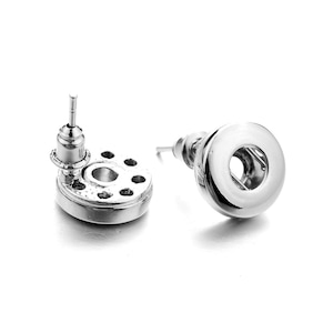 Op de afbeelding: Een paar zilveren oorbelletjes met een rond ontwerp. Eén oorbel heeft een kleine, ronde, zilveren pen met een kleine, ronde, zilveren bovenkant. De andere oorbel heeft een grotere, ronde, zilveren pen met een grotere, ronde, zilveren bovenkant.