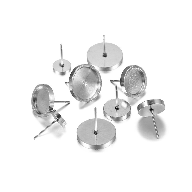 May include: A set of eight silver-toned earring bases with round bezels. The bezels are designed to hold small cabochons or other decorative elements.