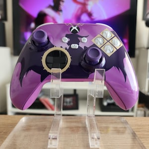Op de afbeelding: Paarse Xbox-controller met een zwart en gouden ontwerp. De controller heeft een drakenontwerp aan de achterkant en het Xbox-logo aan de voorkant.