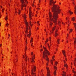Puede incluir: Primer plano de una tela con un patrón abstracto y ardiente. El diseño presenta una mezcla de rojos profundos, naranjas y toques de amarillo, creando una apariencia texturizada, similar a la lava. La superficie de la tela tiene un efecto moteado con formas irregulares más oscuras.