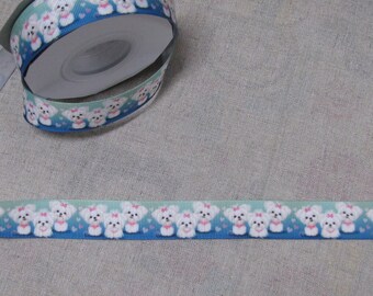 May include: A roll of blue and green ribbon with a white dog print. The ribbon has a repeating pattern of white dogs with pink bows on a blue background with white hearts.