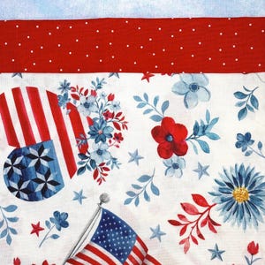 Puede incluir: Un diseño de tela patriótico con una bandera estadounidense, rayas rojas y blancas, patrones florales azules y blancos y estrellas sobre un fondo blanco. Un borde rojo con lunares se encuentra encima del diseño principal, con un fondo azul claro.