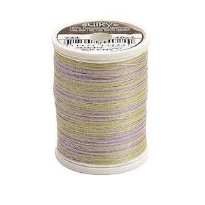 Könnte beinhalten: Eine Spule Sulky 100% Baumwolle mercerisiertes Garn in einer grün-violetten melierten Farbe. Das Etikett lautet "Sulky 100% Baumwolle/Coton Mercerisiert Verwenden Sie eine 90/14 Steppnadel".