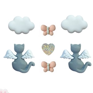 Puede incluir: Un conjunto de seis botones de cerámica gris y blanco con un gato con alas, una nube, un corazón y una mariposa.