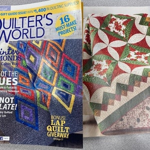 Könnte beinhalten: Zwei Ausgaben des Magazins "Quilter's World" werden gezeigt, die Quilting-Projekte präsentieren. Ein Cover zeigt einen Quilt mit bunten Diamantmustern, das andere zeigt einen Quilt mit roten, grünen und weißen floralen Designs. Der Text enthält "Winter Diamonds" und "I've Got The Blues".