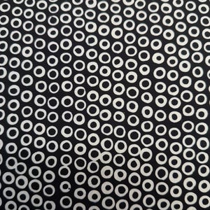 May include: Black and white fabric with a repeating pattern of white circles on a black background.