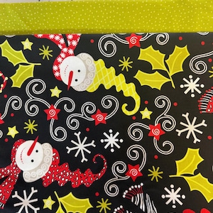 Puede incluir: Tela festiva con fondo negro adornada con muñecos de nieve, copos de nieve, hojas de acebo y estrellas. Los muñecos de nieve llevan bufandas y sombreros rojos y blancos. Un borde verde con lunares blancos completa el diseño.