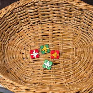 May include: Four small gift boxes in a wicker basket. The boxes are decorated with red, green, and yellow paper and ribbon.