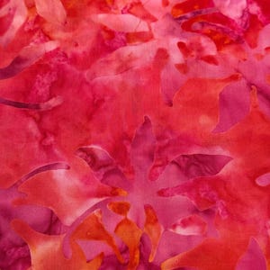 May include: Close-up of a fabric with a batik design. The fabric features a blend of pink, red, and orange hues. The design includes leaf-like shapes and patterns, creating a vibrant and artistic textile.