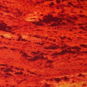 Puede incluir: Primer plano de una tela con un patrón texturizado y ardiente. El diseño presenta tonos de rojo, naranja y marrón oscuro, creando un efecto visual que recuerda a un paisaje volcánico o una puesta de sol.