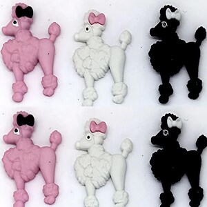 May include: A set of six poodle-shaped buttons arranged in two rows. The top row features a pink poodle with a black bow, a white poodle with a pink bow, and a black poodle with a white bow. The bottom row repeats this exact color sequence.