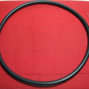 May include: A black rubber hoop, also known as a hula hoop, on a red fabric background.