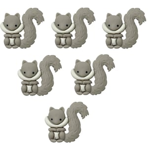 May include: Seven grey squirrel-shaped embellishments are displayed. Each squirrel features a fluffy tail, a white collar, and a light grey body. The squirrels are set against a white backdrop.