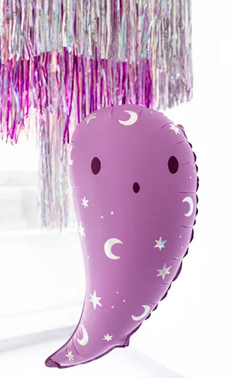 Puede incluir: Un globo morado en forma de fantasma con un patr&oacute;n de media luna y estrellas blancas. El globo tiene una cara simple con dos ojos negros y una peque&ntilde;a boca.