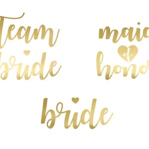 Könnte beinhalten: Drei goldene Folien-Tattoos mit den Worten "Team Bride", "Maid of Honor" und "Bride".