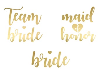 May include: Three gold foil temporary tattoos with the words "Team Bride", "Maid of Honor", and "Bride".