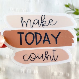 May include: A sticker with three horizontal stripes in shades of peach, brown, and pink. The text "make today count" is written in black cursive font.