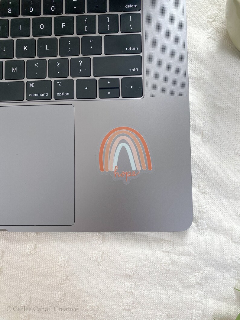 May include: A sticker with a rainbow design in shades of orange, pink, and blue with the word "hope" written in cursive underneath.