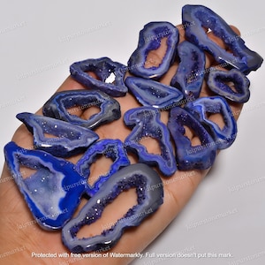 May include: A collection of blue agate crystal slices with a natural hole in the center. The slices are translucent and have a sparkly, iridescent finish.