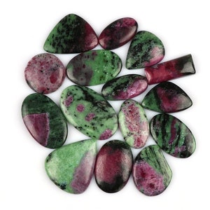May include: A collection of 15 green, pink, and black gemstone cabochons. The stones are various shapes and sizes, with some having a teardrop shape.
