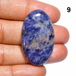 Op de afbeelding: Ovale cabochon edelsteen met een blauw, wit en bruin marmerpatroon. De steen is gepolijst en heeft een gladde, glanzende afwerking.