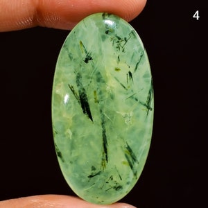 May include: Green aventurine cabochon with black inclusions, oval shaped, approximately 25mm x 18mm.