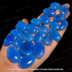 Può includere: Una collezione di 17 pietre preziose lisce, di forma ovale, di colore blu chiaro. Le pietre preziose sono disposte in una mano, alcune si sovrappongono.