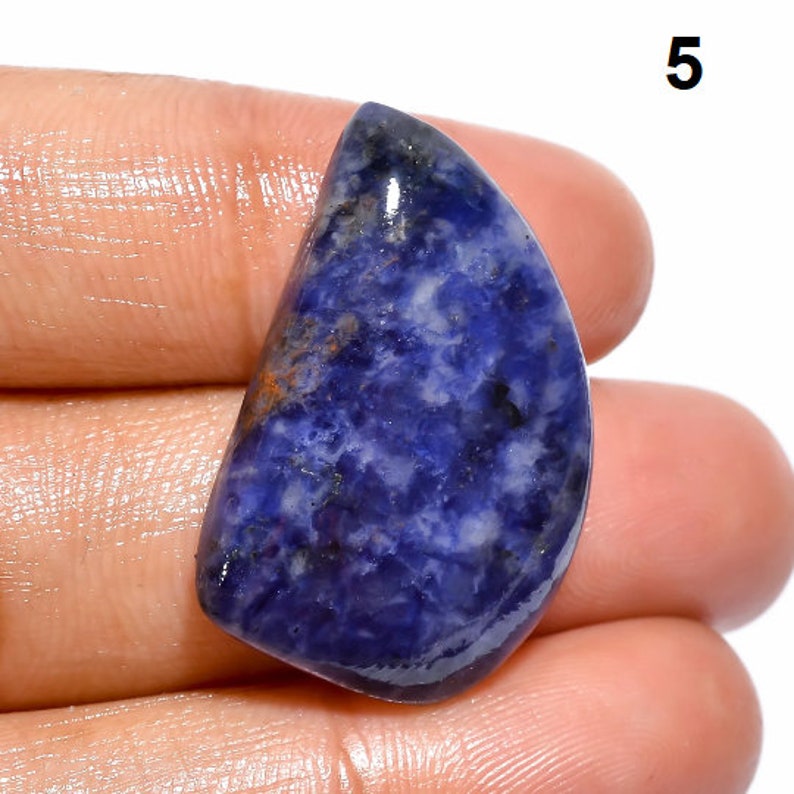 Op de afbeelding: Een close-up van een blauwe en witte cabochon edelsteen met een glad, gepolijst oppervlak. De edelsteen is halfrond en heeft een lichtblauwe kleur met witte swirls en strepen.