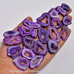 May include: A collection of purple agate slices with a natural crystal formation. The slices are translucent and have a variety of shapes and sizes. The agate is a semi-precious gemstone known for its beauty and healing properties.