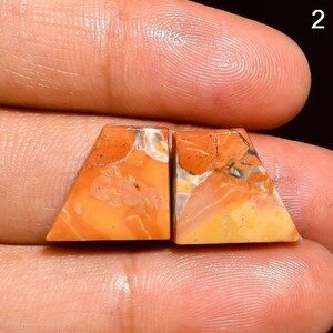 May include: Pair of orange, yellow and white agate cabochons with a triangular shape. The cabochons are set in a bezel setting and are ready to be used in jewellery making.