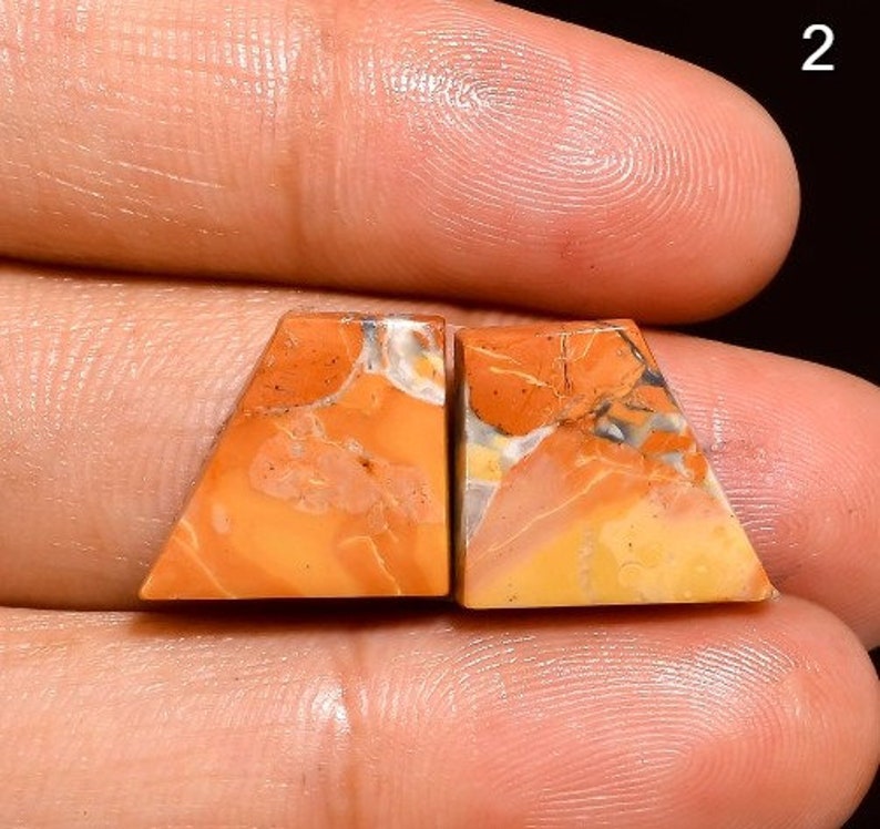 May include: Pair of orange, yellow and white agate cabochons with a triangular shape. The cabochons are set in a bezel setting and are ready to be used in jewellery making.