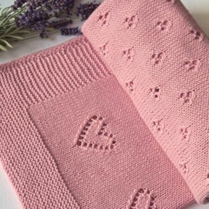 Può includere: Una copertina per neonati in maglia rosa con un motivo a forma di cuore. La copertina è realizzata in cotone morbido e traspirante, perfetta per coccolare.