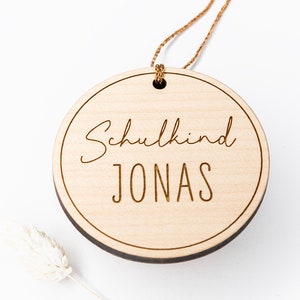 Holzanhänger ist mit dem Text "Schulkind" graviert.