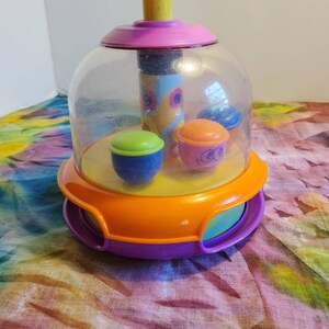 Vintage Spinning Baby Kleinkind Schiebespielzeug. Knopf nach unten drücken und schon rollen die kleinen Leute herum und wirbeln herum.