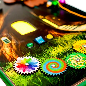 Pode incluir: Um brinquedo de madeira com design de casa na &aacute;rvore, com engrenagens coloridas, bot&otilde;es e uma janela que se ilumina. O brinquedo &eacute; projetado para que as crian&ccedil;as explorem e aprendam brincando.
