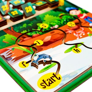 Pode incluir: Um jogo de labirinto de madeira com um tema de selva colorido. O labirinto apresenta um caminho com letras e n&uacute;meros, um peixe azul, uma raposa vermelha e um sapo verde. O jogo inclui um marcador de in&iacute;cio amarelo e um cord&atilde;o preto para guiar o caminho.