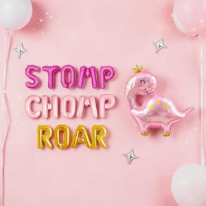 May include: Pink and gold foil balloons spelling out "STOMP CHOMP ROAR" on a pink background. A pink dinosaur balloon with a gold crown is also present, along with star-shaped and round balloons.