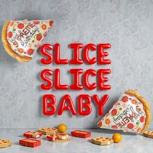 May include: A birthday display featuring red balloon letters spelling "SLICE SLICE BABY." Two pizza slice balloons with "Have a Supreme Birthday!" text are visible. Miniature pizzas and oranges are arranged on a surface.