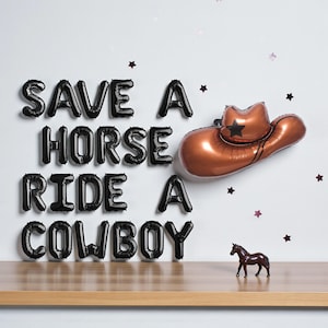 May include: A decorative arrangement featuring black balloon letters spelling "SAVE A HORSE RIDE A COWBOY". A copper-colored cowboy hat balloon and a small brown horse figurine are also present, with star-shaped confetti.