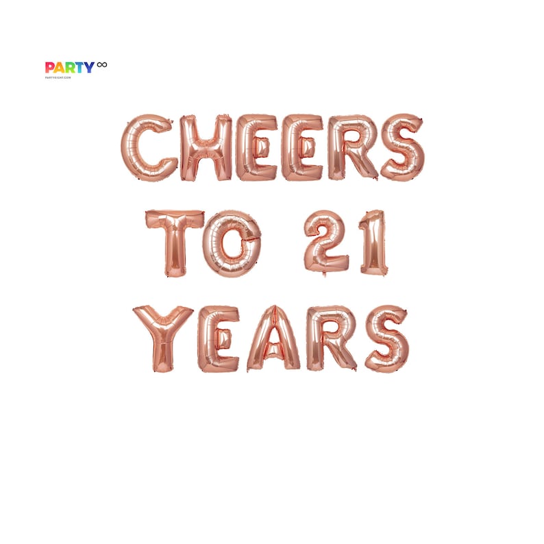 Peut inclure: Ballons en feuille d'or rose &eacute;pelant "CHEERS TO 21 YEARS" sur fond blanc. Les ballons sont dispos&eacute;s sur trois lignes, les mots &eacute;tant centr&eacute;s. Le logo du fournisseur de f&ecirc;te est en haut &agrave; gauche.
