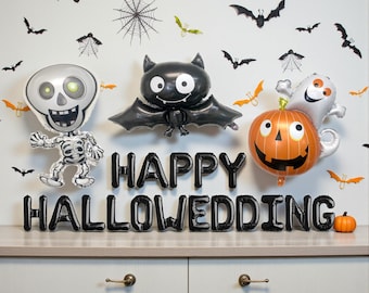 May include: A Halloween-themed display featuring inflatable balloons shaped like a skeleton, bat, pumpkin, and ghost. The phrase "HAPPY HALLOWEDDING" is spelled out in black balloons. Decorative bats and spiderwebs adorn the white wall.
