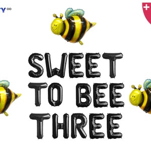 May include: A set of black foil balloons spelling "SWEET TO BEE THREE" with three yellow and black bee-shaped balloons. Includes a balloon straw and string. Party decor for a third birthday.