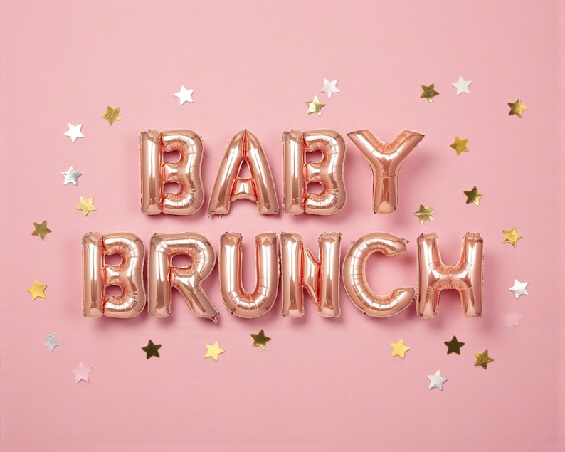May include: Rose gold foil balloons spelling out "BABY BRUNCH" on a pink background, scattered with gold and silver star-shaped confetti. A festive and celebratory theme.