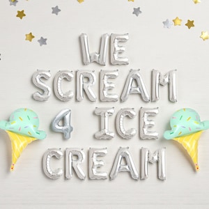 Puede incluir: Una composición festiva con globos plateados que deletrean "WE SCREAM 4 ICE CREAM". Dos globos de cono de helado con helado verde menta y conos amarillos. Confeti de estrellas plateadas y doradas decora el fondo blanco.