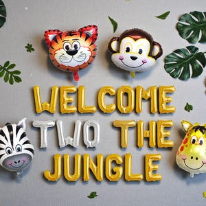 K&ouml;nnte beinhalten: Dekoration f&uuml;r eine Dschungelparty mit Tierballons: Tiger, Affe, Zebra und Giraffe. Goldene und silberne Buchstabenballons bilden die Aufschrift "WELCOME TWO THE JUNGLE". Gr&uuml;ne Bl&auml;tter erg&auml;nzen die Partydekoration.