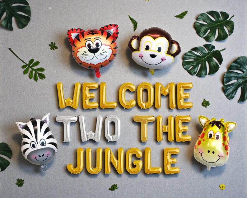 K&ouml;nnte beinhalten: Dekoration f&uuml;r eine Dschungelparty mit Tierballons: Tiger, Affe, Zebra und Giraffe. Goldene und silberne Buchstabenballons bilden die Aufschrift "WELCOME TWO THE JUNGLE". Gr&uuml;ne Bl&auml;tter erg&auml;nzen die Partydekoration.