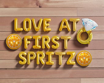 Decoración con globos para despedida de soltera "Love at First Spritz": globos naranjas y con forma de anillo