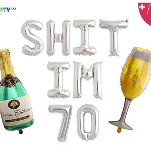 May include: A collection of silver foil balloons spelling "SHIT IM 70", a champagne bottle balloon, and a champagne glass balloon. The champagne bottle is green and gold with the text "Chateau C&eacute;l&eacute;brale". The champagne glass balloon says "Cheers".